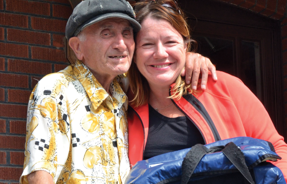 volunteer delivering Meals on Wheels to elderly man