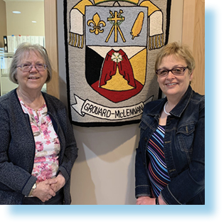 two women in front of the Roman Catholic Archdiocese of Grouard-McLennan banner