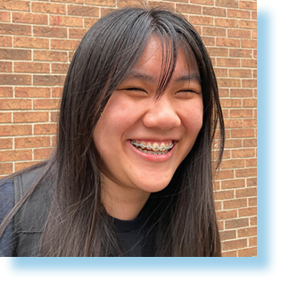 smiling teenaged girl against a brick wall