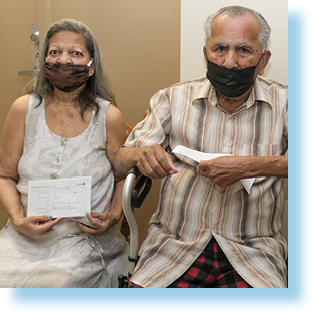 Man and woman sitting on chair and wearing masks.