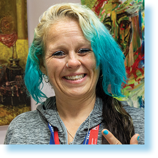 smiling woman standing in front of two paintings