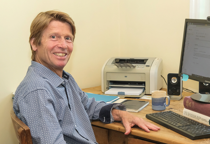 Man sitting at desk with computer and smiling