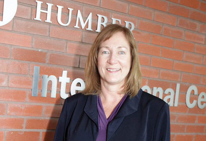 Woman standing against the Humber sign and smiling