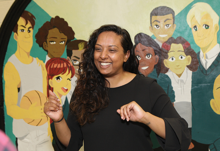 Woman standing in front of a mural, smiling