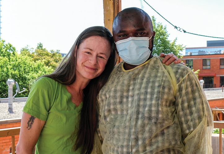 Woman standing with her hand over mans shoulder and smiling