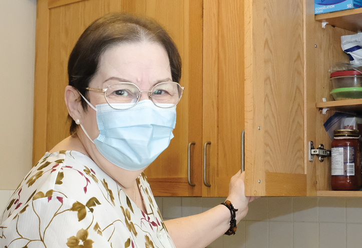 Woman wearing a mask and opening a cupboard