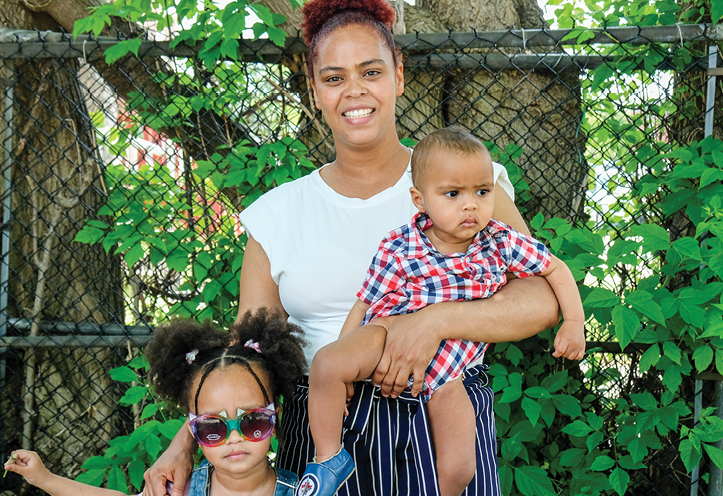 Woman standing with daughter and holding son in her arms