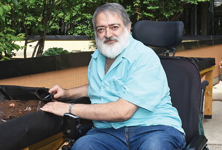 man in wheelchair working in backyard garden