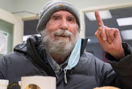 elderly man in Corner Drop-in raising a finger