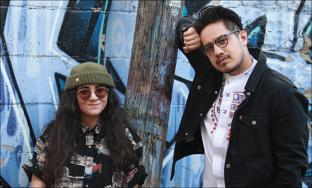 youth standing against blue wall with graffiti