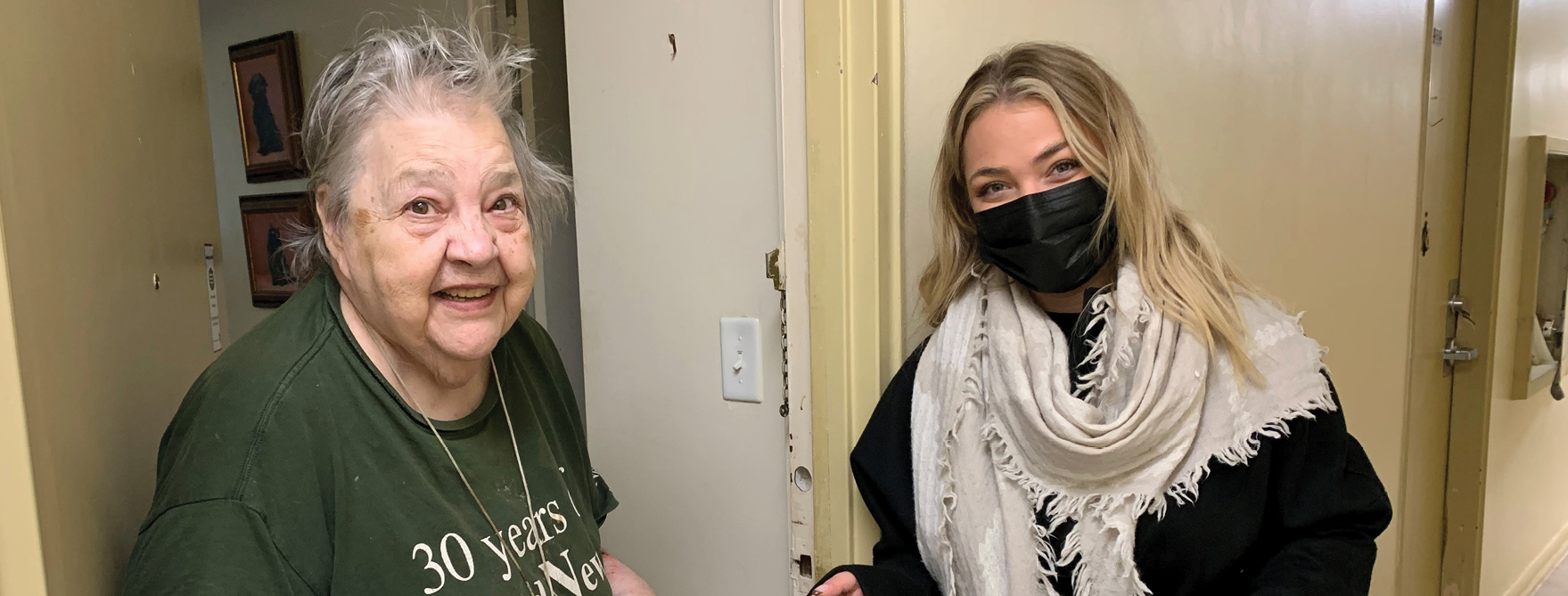 elderly woman at front door of her apartment and volunteer