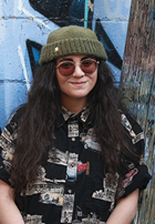 teen girl standing with graffiti on wall behind her